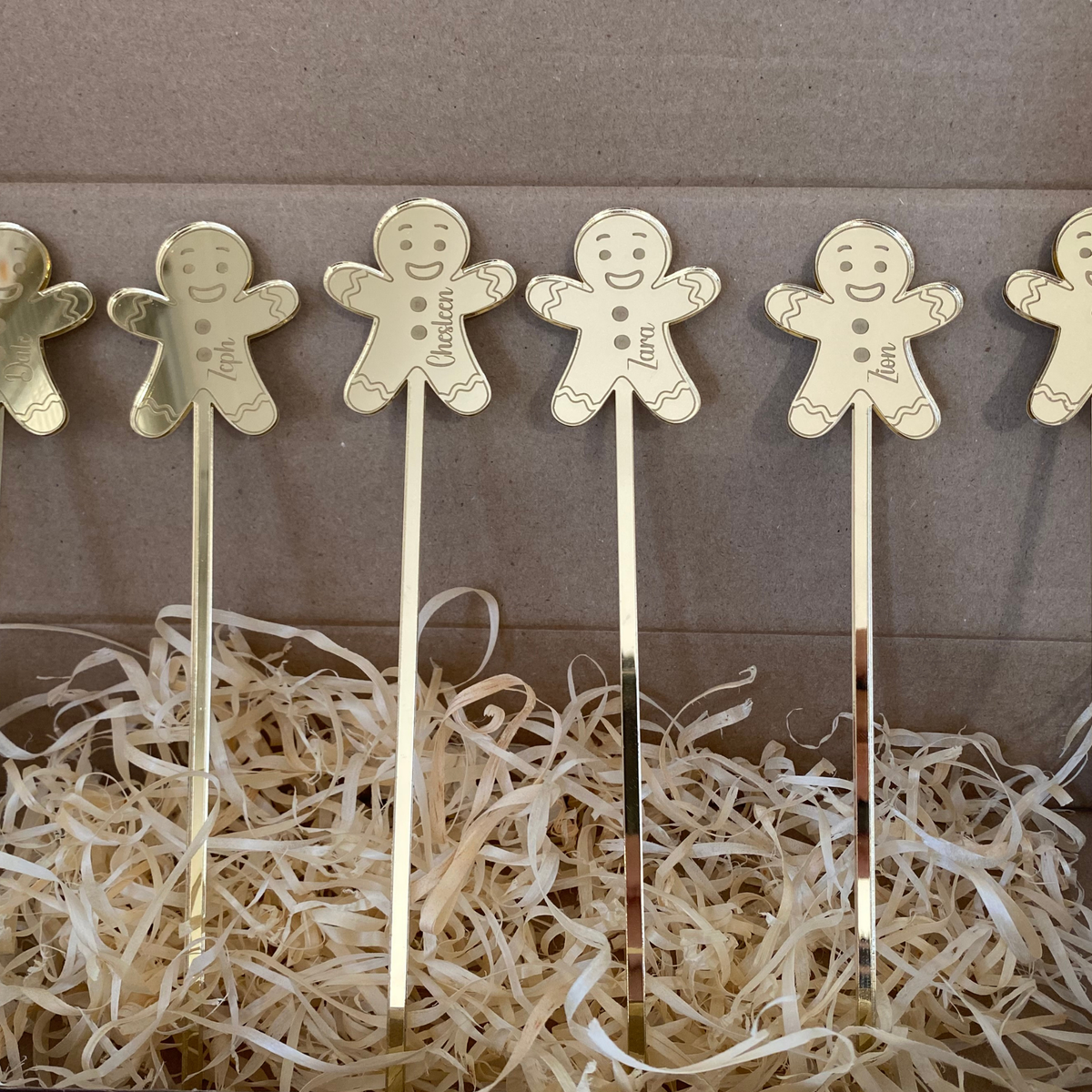 Personalised Christmas drink stirrers with gingerbread man designs displayed together in decorative packaging