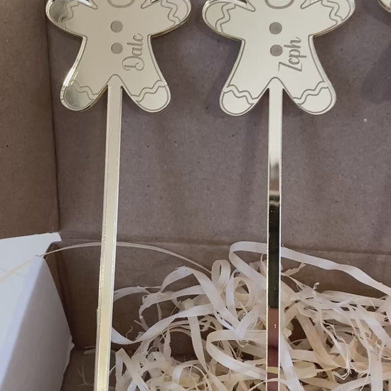 Personalised acrylic Christmas drink stirrers featuring engraved gingerbread man designs displayed against a festive background.